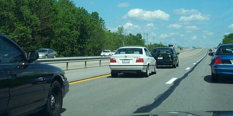 2001 Ford Crown Victoria - A black sedan is seen driving on a highway with other vehicles.