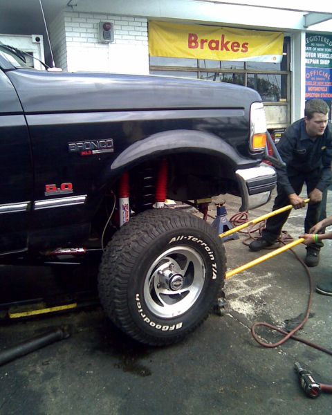1995 Ford Bronco - A black 1995 Ford Bronco is being serviced, showing its lifted suspension and large tires.