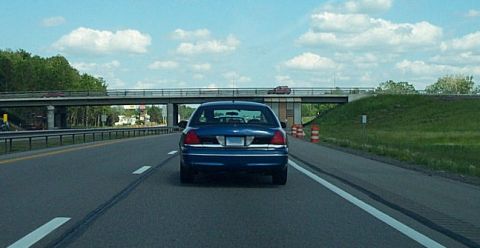 2001 Ford Crown Victoria - Rear view of a blue 2001 Ford Crown Victoria driving on a highway under an overpass.