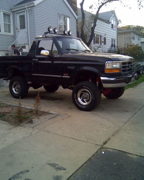 1995 Ford Bronco - This black Ford Bronco is parked in front of a residential house.