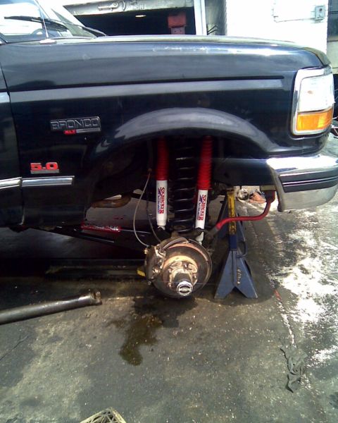 1995 Ford Bronco - Front suspension of a 1995 Ford Bronco, showing lifted components and red shocks.