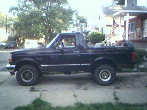 1995 Ford Bronco - Side profile of a black 1995 Ford Bronco with a spare tire mounted in the bed.