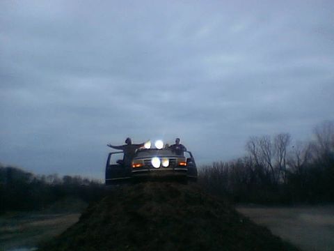 1995 Ford Bronco - This 1995 Ford Bronco is seen from the front, with two individuals standing on its roof and auxiliary lights illuminated.