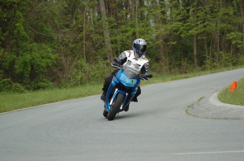 2007 Kawasaki Ninja R - Rider on a blue sportbike navigates a turn on a track, with trees lining the course.