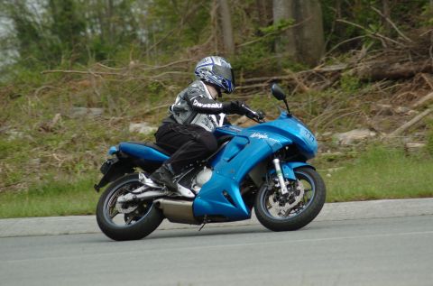 2007 Kawasaki Ninja R - A rider on a blue 2007 Kawasaki Ninja R motorcycle is seen from the side on a paved road.