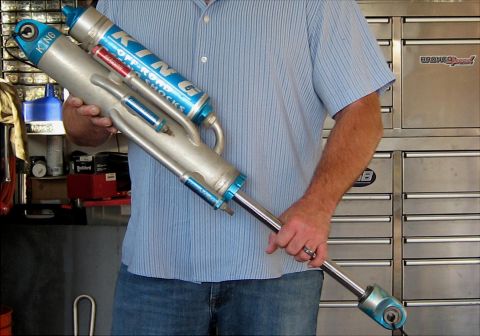 1996 Ford Bronco - King Off-Road Shocks are held by a person in front of a tool chest.