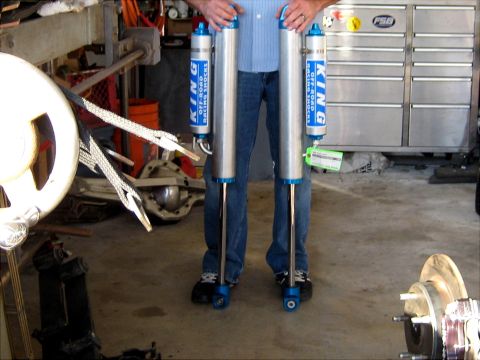 1996 Ford Bronco - A person holds two King Off-Road Racing Shocks, which are silver with blue accents and readable text.