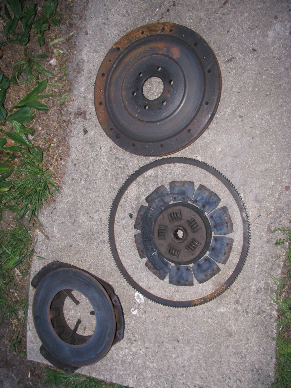 Clutch disc, pressure plate, and flywheel laid out on concrete
