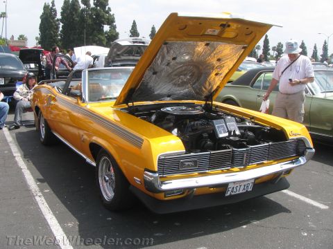 1968 Ford Mustang - A yellow 1969 Mercury Cougar convertible is displayed with its hood open at an outdoor car show.