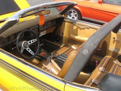 1968 Ford Mustang - Interior view of a yellow convertible brown striped seats and a Cougar emblem, with another orange car visible in the background.