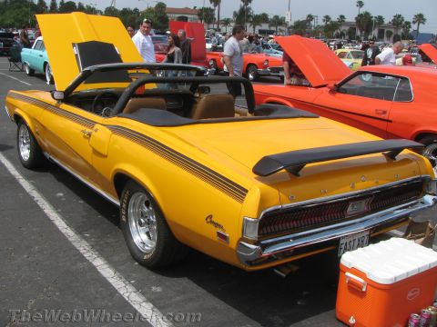 1968 Ford Mustang - A yellow 1969 Mercury Cougar convertible is parked at an outdoor car show with other vehicles.