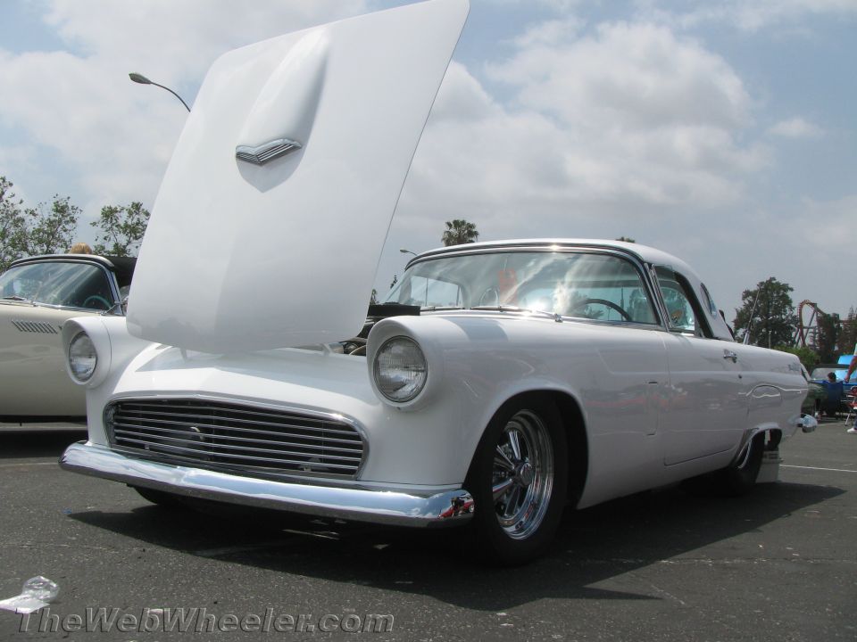 White 1955 Ford Thunderbird coupe with hood open, front 3/4 view, chrome grille and bumper, aftermarket wheels