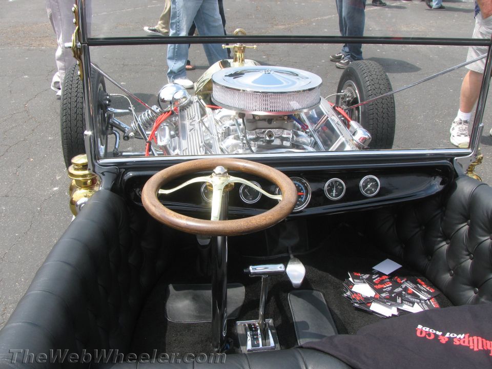 Hot rod interior with wood steering wheel, chrome engine, and black tufted seats