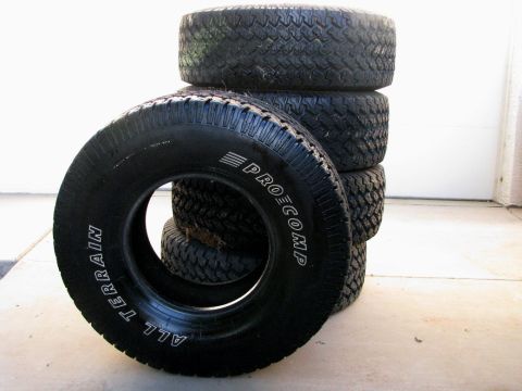 2008 Ford Bronco - Four Pro Comp All Terrain tires are stacked on a concrete surface.