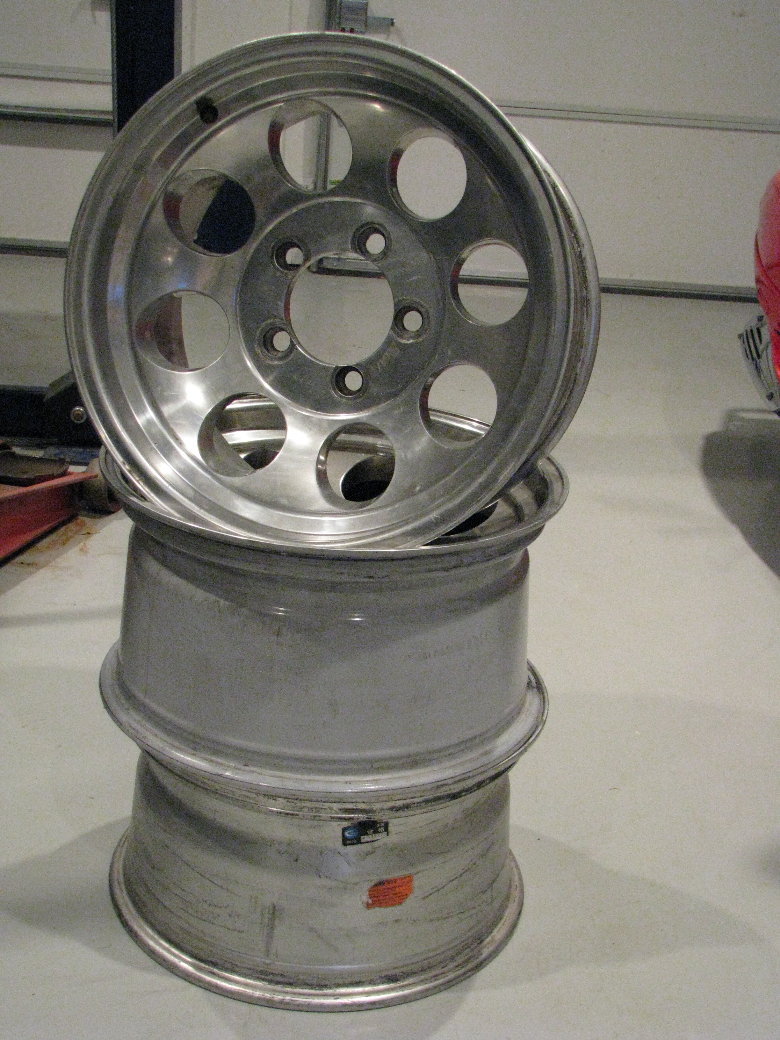 stack of three aluminum wheels, one on top with holes