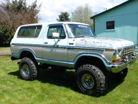 1978 Ford Bronco - This lifted 1978 Ford Bronco features a two-tone paint scheme of light blue and silver, complemented by large off-road tires.