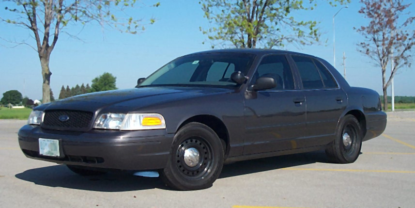 Dark gray Ford Crown Victoria Police Interceptor sedan on black steel wheels in a parking lot
