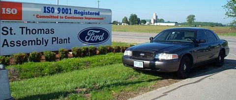 2001 Ford Crown Victoria - Dark grey Ford Crown Victoria Police Interceptor parked on the grass beside the "St. Thomas Assembly Plant" Ford sign, which also reads "IS…