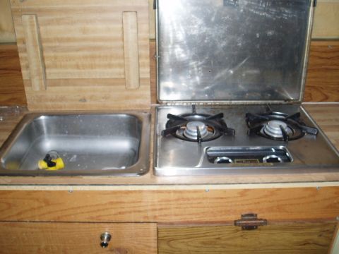 1980 Ford Bronco - This image shows a built-in kitchen counter with a sink and a two-burner stovetop, likely in an RV or camper.