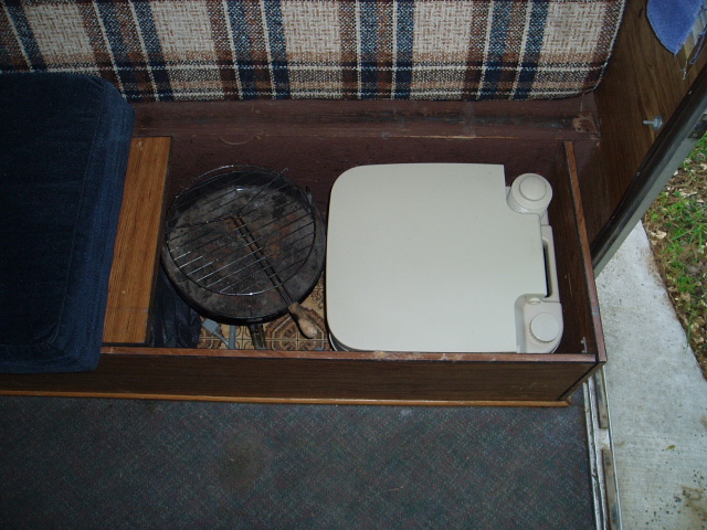 Interior storage compartment with portable toilet and grill