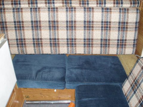 1980 Ford Bronco - The interior of a camper features a blue couch and plaid curtains, suggesting a living space within a vehicle.