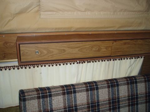 1980 Ford Bronco - The interior of a vehicle shows wood paneling with text and a plaid fabric covering.