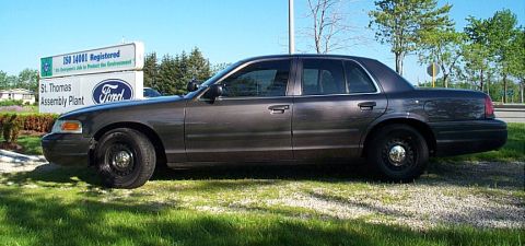 2001 Ford Crown Victoria - A 2001 Ford Crown Victoria sedan is parked on a grassy area next to the St. Thomas Assembly Plant sign.