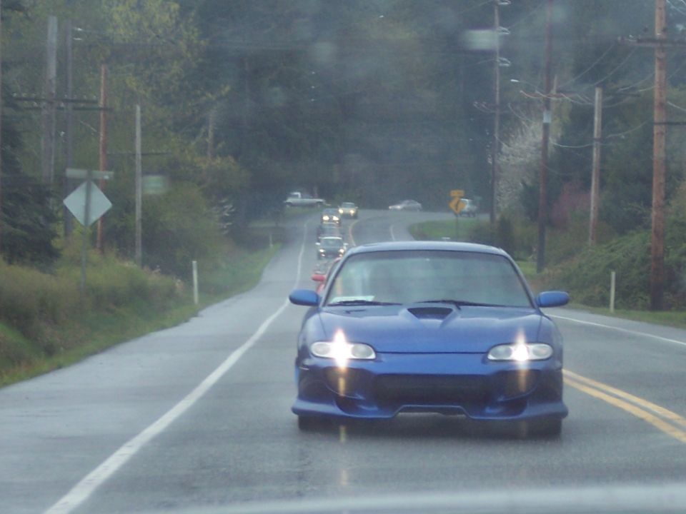 Blue sports coupe driving on a wet road