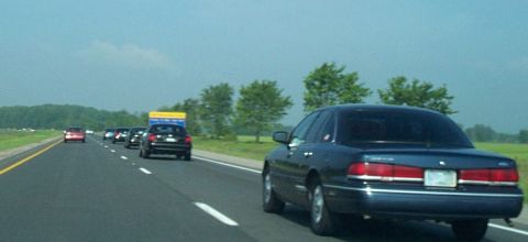 2001 Ford Crown Victoria - Driving on the highway behind a dark blue 2001 Ford Crown Victoria with other vehicles in traffic.