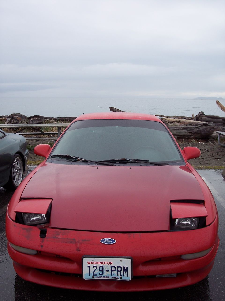 Red 1995 Ford Probe with Washington license plate 129-PRM parked by the water.