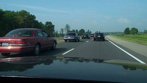 2001 Ford Crown Victoria - A red sedan is seen from the perspective of another vehicle on a highway with other cars in traffic.
