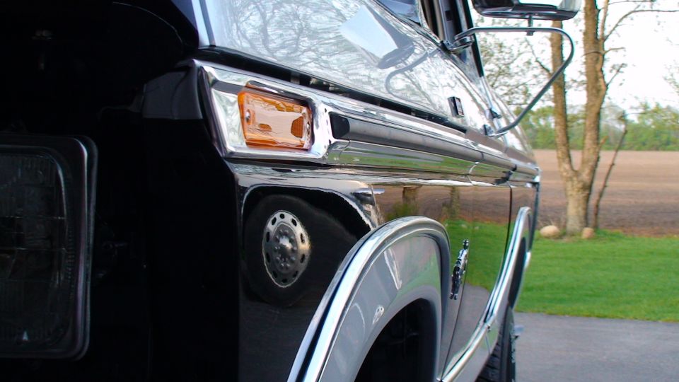 Black vehicle side view, showing chrome trim, headlight, and turn signal.