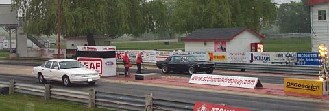 2001 Ford Crown Victoria - Two cars are lined up at the start of a drag race, with advertising banners visible.