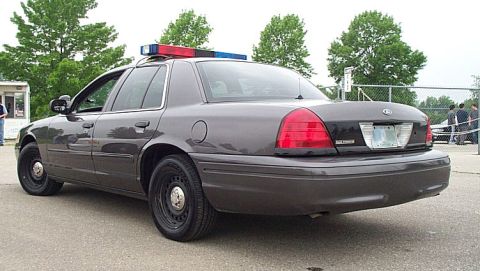 2001 Ford Crown Victoria - This police car, likely a 2001 Ford Crown Victoria, is seen from the rear three-quarter angle, equipped with a light bar on the roof.