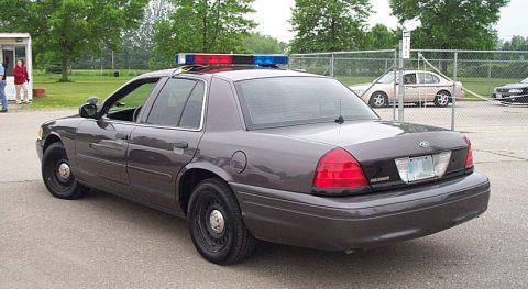 2001 Ford Crown Victoria - Rear view of a dark gray 2001 Ford Crown Victoria police car with a light bar.