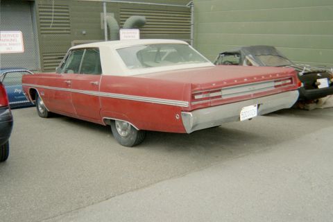 1972 Ford Ranchero - A red and white two-door sedan is parked on asphalt next to a chain-link fence. The car has chrome trim and a license plate that reads "500…