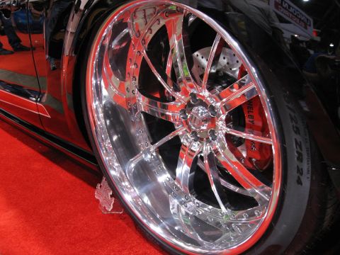1998 Ford Crown Victoria - Chrome wheel detail on a red car, likely aftermarket.