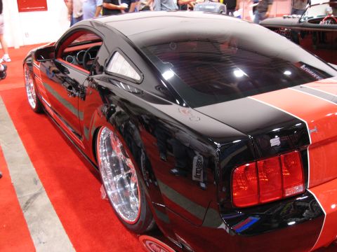 1998 Ford Crown Victoria - A customized Ford Mustang is displayed on a red carpet with racing stripes.