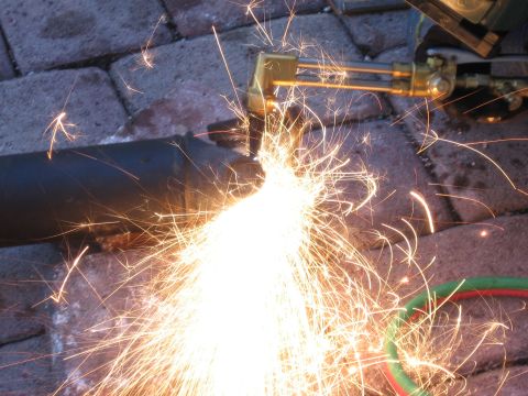 1995 Ford F-150 - A close-up shot shows a metal pipe being cut with a torch, creating a shower of bright orange sparks. The sparks illuminate the surrounding…