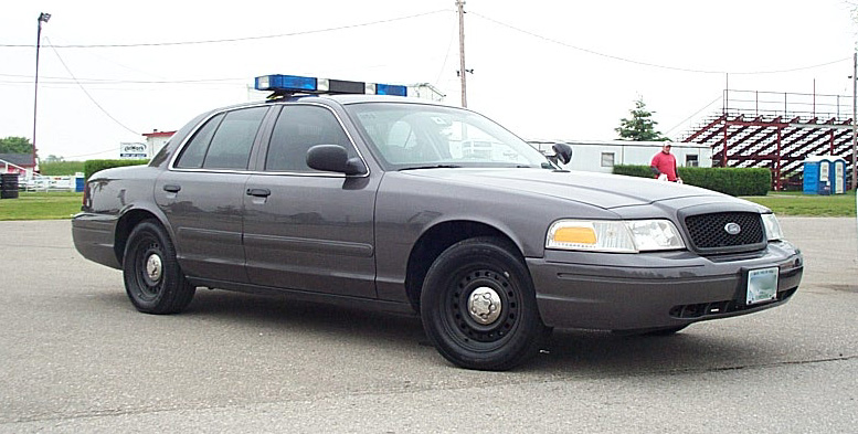 gray police car, front quarter view, light bar on roof