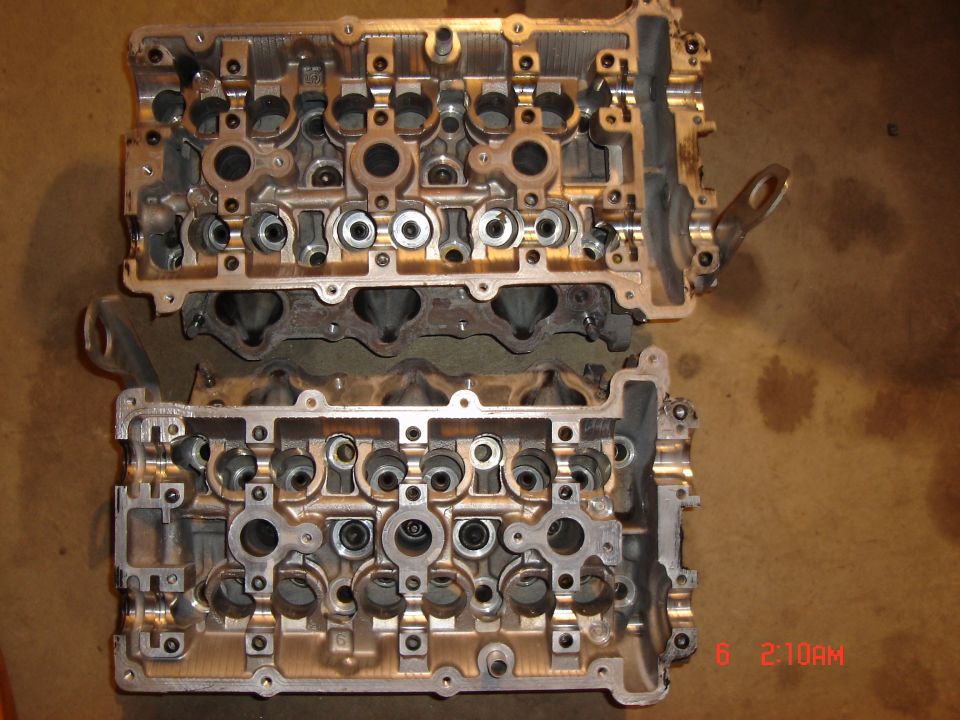 Two aluminum engine cylinder heads stacked.