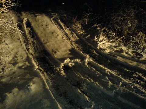 1989 Ford Bronco - Tire tracks are visible in the snow on a dark, possibly rural road.