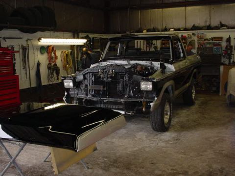 1979 Ford Bronco - Ford Bronco undergoing repairs in a workshop, with its hood removed and placed on a stand.