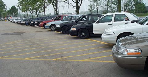 2001 Ford Crown Victoria - Multiple Ford Crown Victoria police cars are parked in a lot, showing their side profiles.