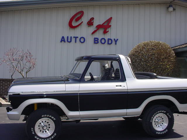 Two-tone black and white Ford Bronco parked in front of C&A Auto Body