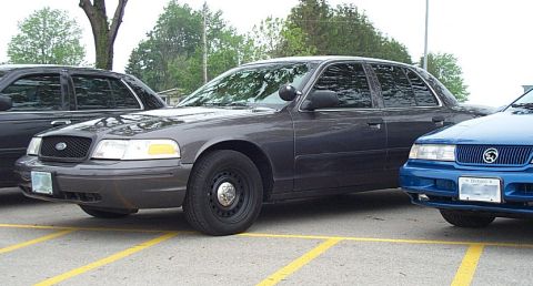 2001 Ford Crown Victoria - A dark gray 2001 Ford Crown Victoria sedan is parked next to a blue car.