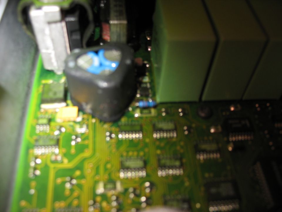 Circuit board with a black inductor and green capacitors