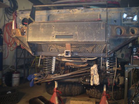 1986 Ford Bronco - Front end of a vehicle being worked on, showing suspension and custom bumper.