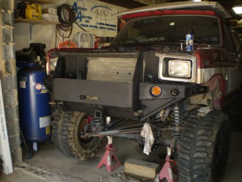 1986 Ford Bronco - This modified Ford Bronco features a custom bumper and large off-road tires, suggesting it's being prepared for terrain.