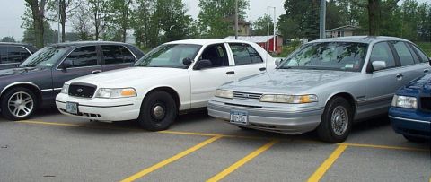 2001 Ford Crown Victoria - A silver 2001 Ford Crown Victoria is parked next to a white sedan and a dark sedan.